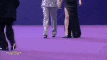 a group of people walking on a purple carpet