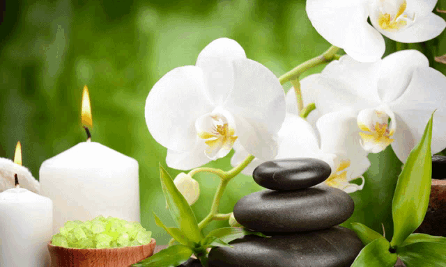 a stack of rocks next to a bowl of green salt and a candle