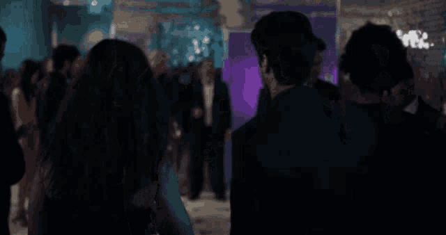 a group of people are standing in a room with purple lights