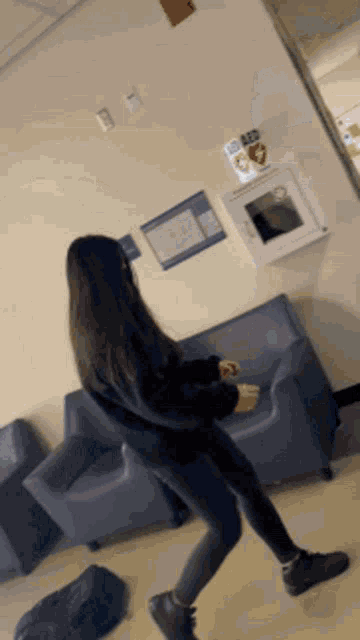 a woman is dancing in a hallway with a aed box on the wall behind her