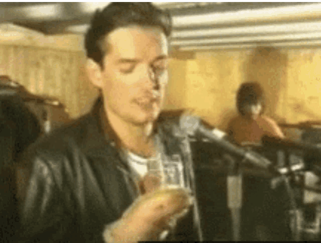 a man in a leather jacket is holding a glass