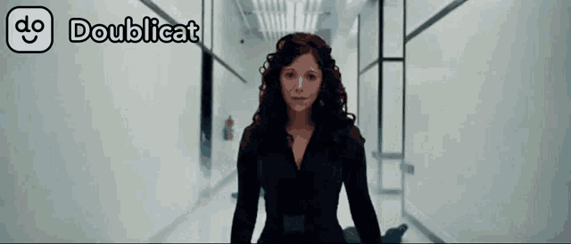 a woman in a black suit is standing in a hallway with doublecat written on the bottom right