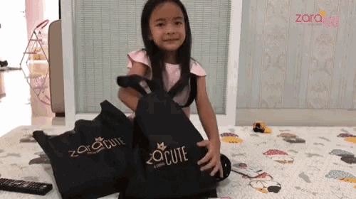 a little girl holding a black bag that says cute