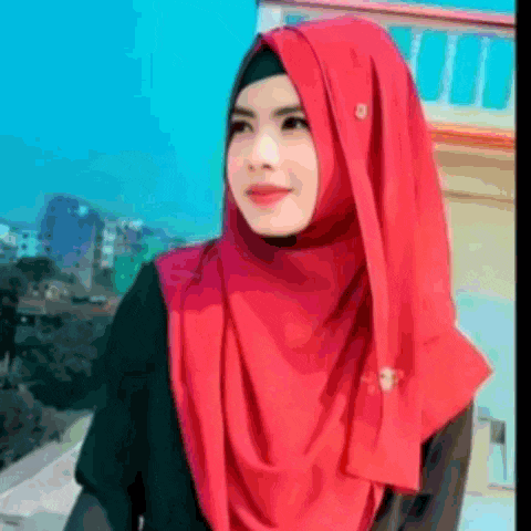 a woman wearing a red hijab and a black shirt is standing in front of a building