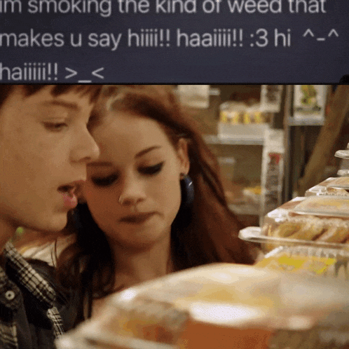 a man and a woman are looking at food in front of a sign that says i 'm smoking the kind of weed
