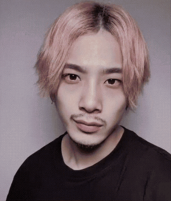 a young man with pink hair and a beard wears a black shirt