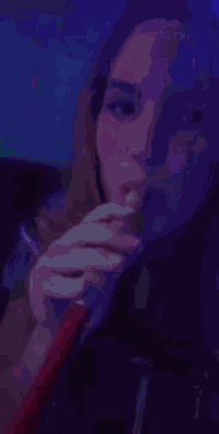 a woman is smoking a hookah in a dark room with smoke coming out of her mouth .