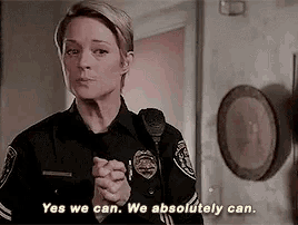 a woman in a police uniform is talking into a microphone and saying `` yes we can . we absolutely can . ''