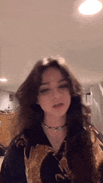 a girl with long hair is standing in a room wearing a choker and a black shirt .
