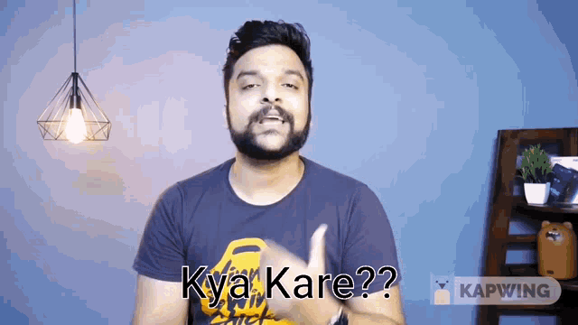 a man with a beard is wearing a black shirt and says kya kare