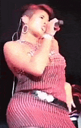 a woman in a red striped dress is singing into a microphone on a stage .
