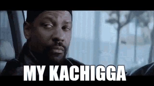 a man with a beard is sitting in a car with the words `` my kachiga '' written on the screen .