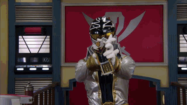 a man in a silver and black costume is holding a remote control