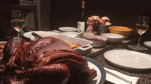 a turkey and ham are on a plate on a table with a bottle of wine