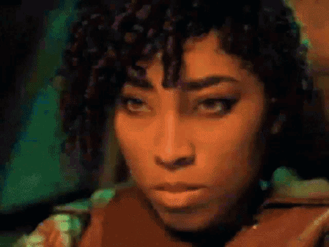 a close up of a woman 's face with curly hair and a green background .