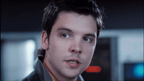 a close up of a man 's face with a blue light behind him