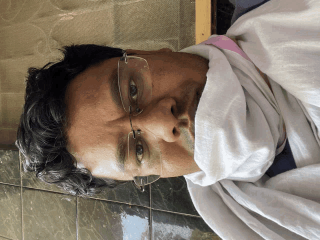 a man wearing glasses and a white scarf covering his mouth