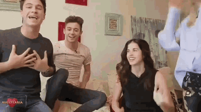 a group of people are sitting on a couch and one of them is wearing a shirt that says ruggelaria on it