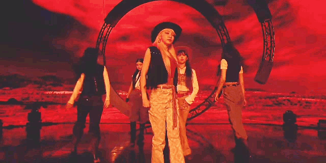 a group of women are dancing together on a stage . one of the women is wearing a cowboy hat .