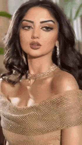 the woman is wearing a gold dress and a necklace .