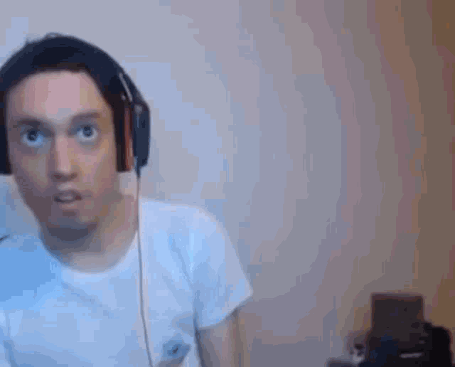 a man wearing headphones and a white shirt is making a surprised face .