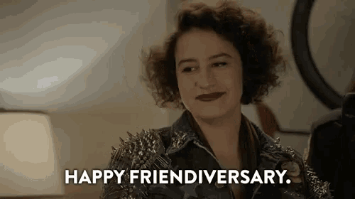 a woman wearing a denim jacket with spikes on the sleeves is smiling and saying `` happy friendivery '' .
