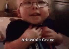 a little boy wearing glasses is laying on a bed and says `` adorable grace '' .