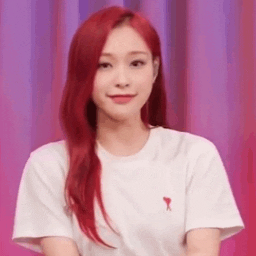 a woman with red hair is wearing a white t-shirt and making a funny face .