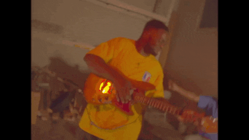 a man is playing a guitar in front of a neon sign