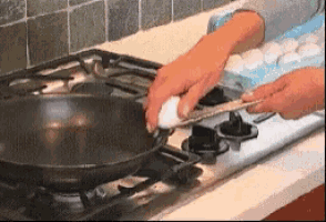 a person is cracking an egg into a pan on a stove