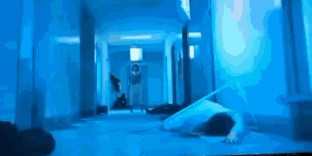 a person is laying on the floor in a hallway with a blue light shining on them .