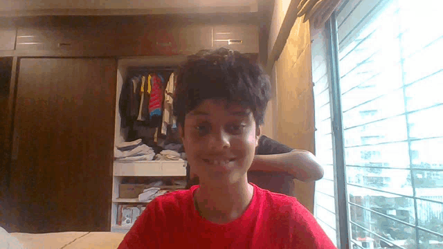 a young boy in a red shirt is smiling for the camera
