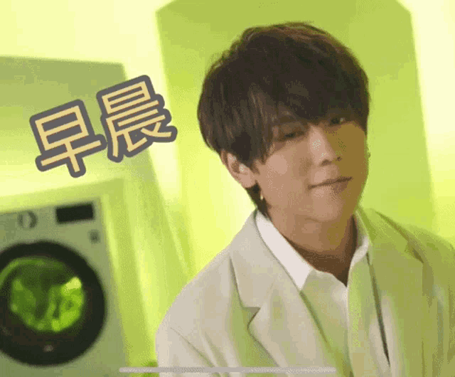 a young man in a white suit is standing in front of a washing machine .