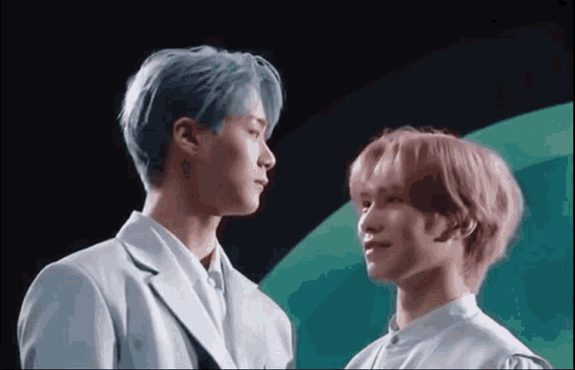 a man with blue hair and a man with pink hair are touching foreheads