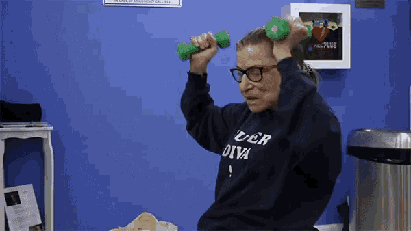 a woman wearing a sweater that says uber diva is lifting dumbbells