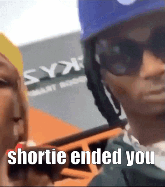 a man wearing sunglasses and a blue helmet is standing next to a woman and says shortie ended you
