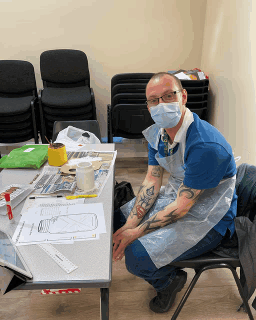 a man wearing a mask sits in front of a table