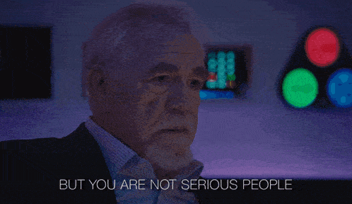 a man in a suit says " but you are not serious people " in a dark room