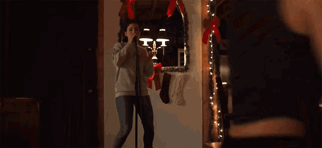 a woman singing into a microphone in front of a christmas decoration