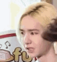 a close up of a person 's face with a cake in the background .
