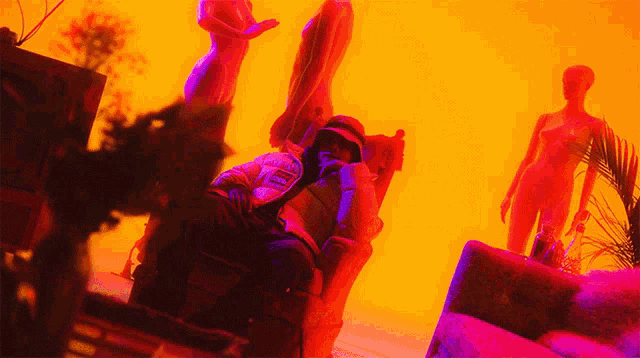 a man is sitting in a chair in front of a naked mannequin