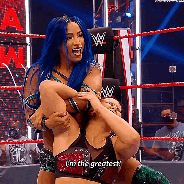 a wrestler with blue hair is holding another wrestler on her shoulders and says i 'm the greatest