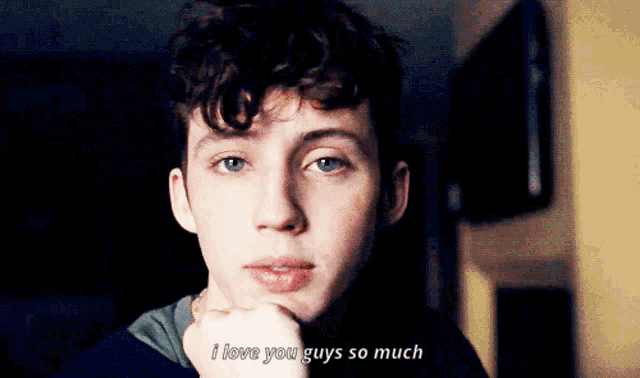 a young man says " i love you guys so much " with his hand on his chin