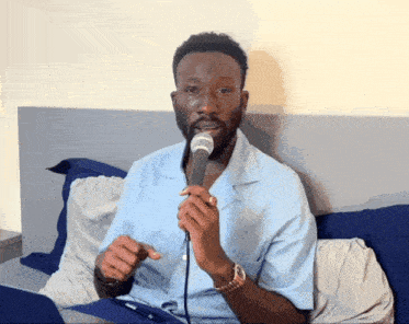 a man sitting on a bed with a microphone in his hand