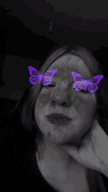 a black and white photo of a woman with purple butterflies on her face