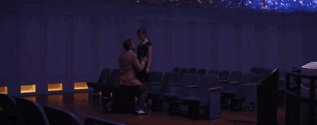 a woman in a green dress is jumping in the air while a man stands behind her