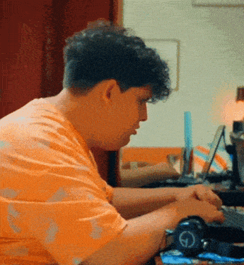 a man in an orange shirt is typing on a keyboard