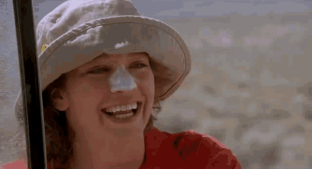 a woman wearing a hat with sunscreen on her face