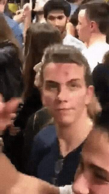 a man with a blood spot on his forehead is standing in a crowd of people