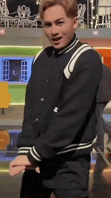 a man wearing a black jacket and black pants is standing in front of a stage .